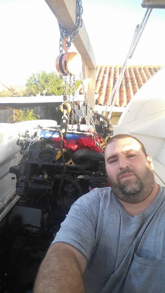 Selfie con un motor colgando de una grúa de cadena