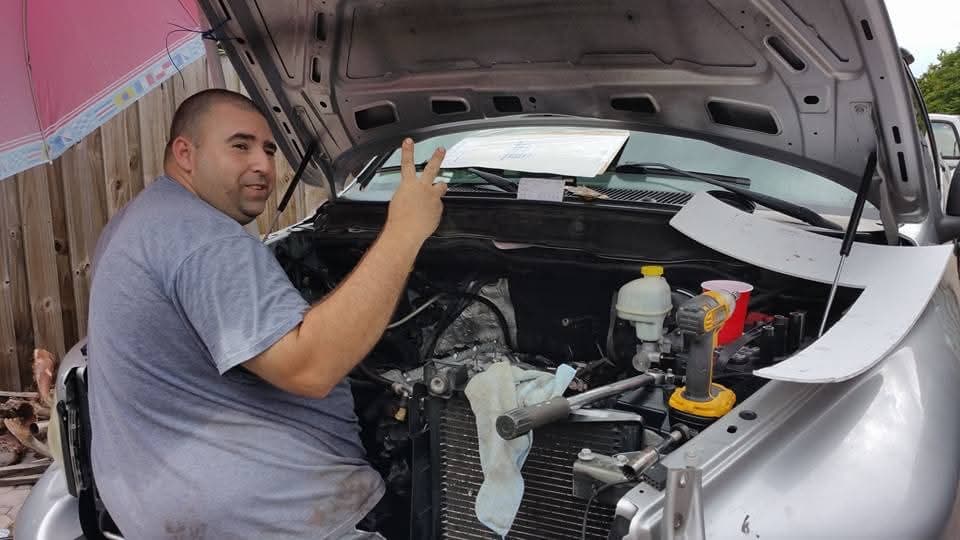 Señal de paz desde abajo del capó de una camioneta plateada